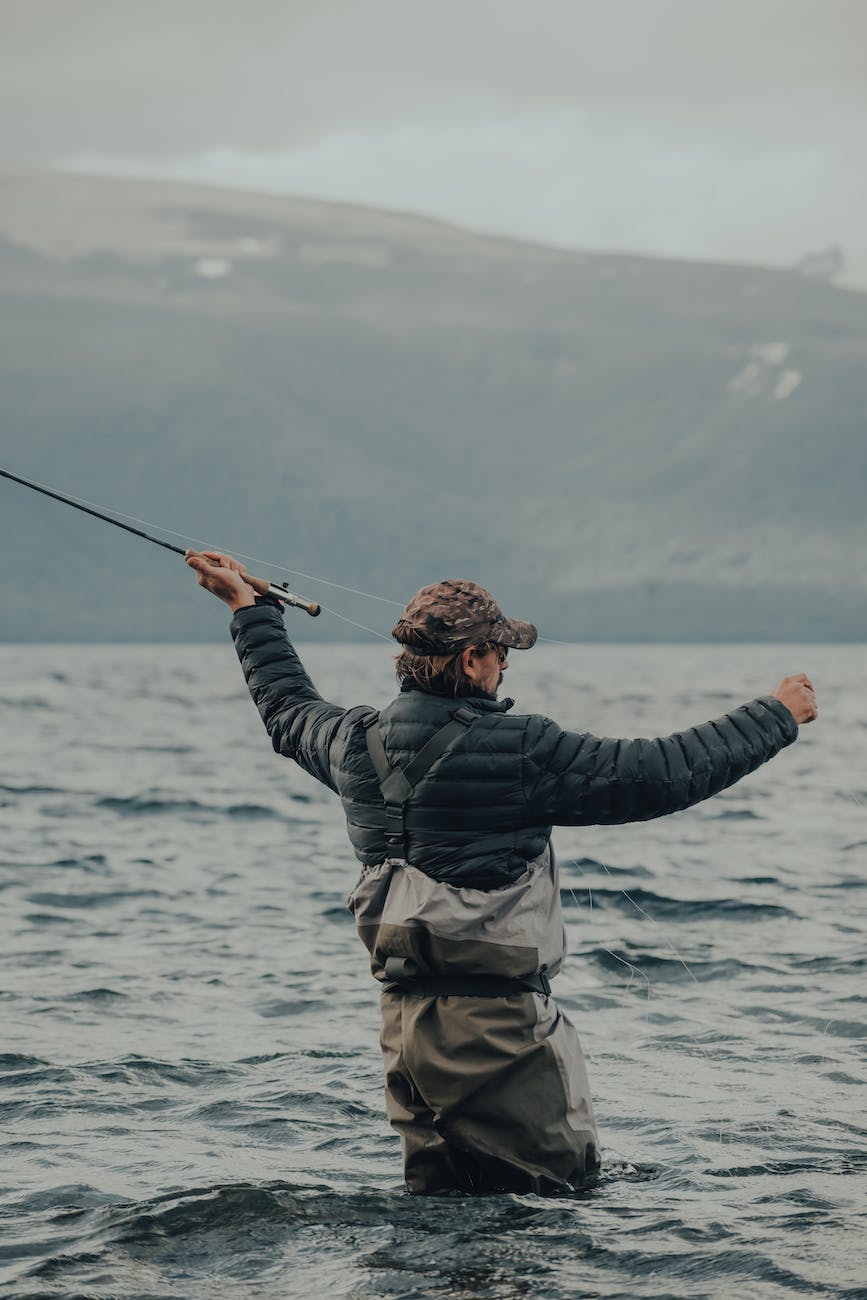 man in black jacket and brown pants holding black fishing rod